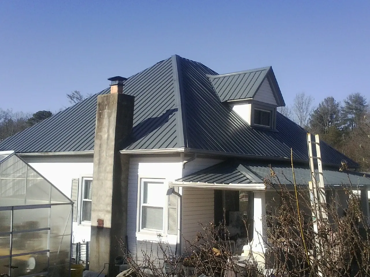 Dark blue standing seam metal roof on a white farmhouse with dormer — Slate & Tile Roof Repair by Roofing Brothers in Tennyson