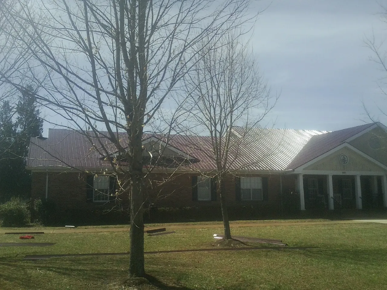 Red metal roof on a brick building seen from the front lawn in Tennyson