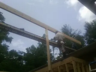 Carpenter setting a ridge beam over a new addition frame — Ice Dam Removal by Roofing Brothers in Tennyson