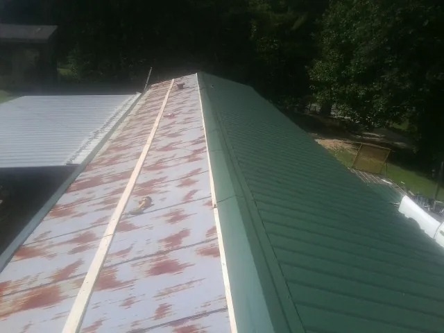 Old rusted panels beside newly installed green metal roofing — Wind Damage Roof Repair by Roofing Brothers in Tennyson