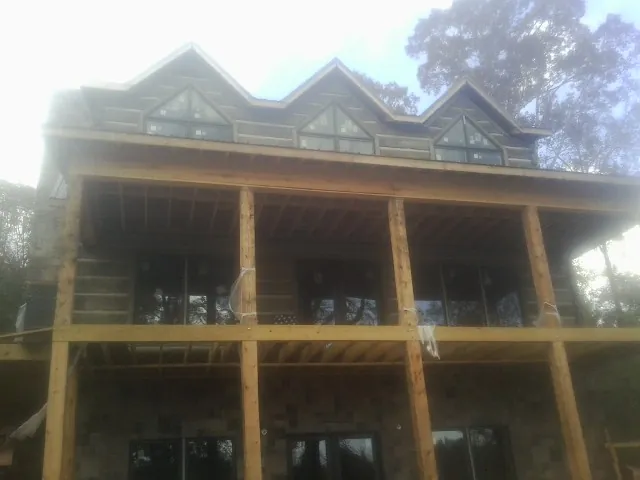 Dormers and porch framing on a large log home under construction — Roof Coating work by our crew in Tennyson