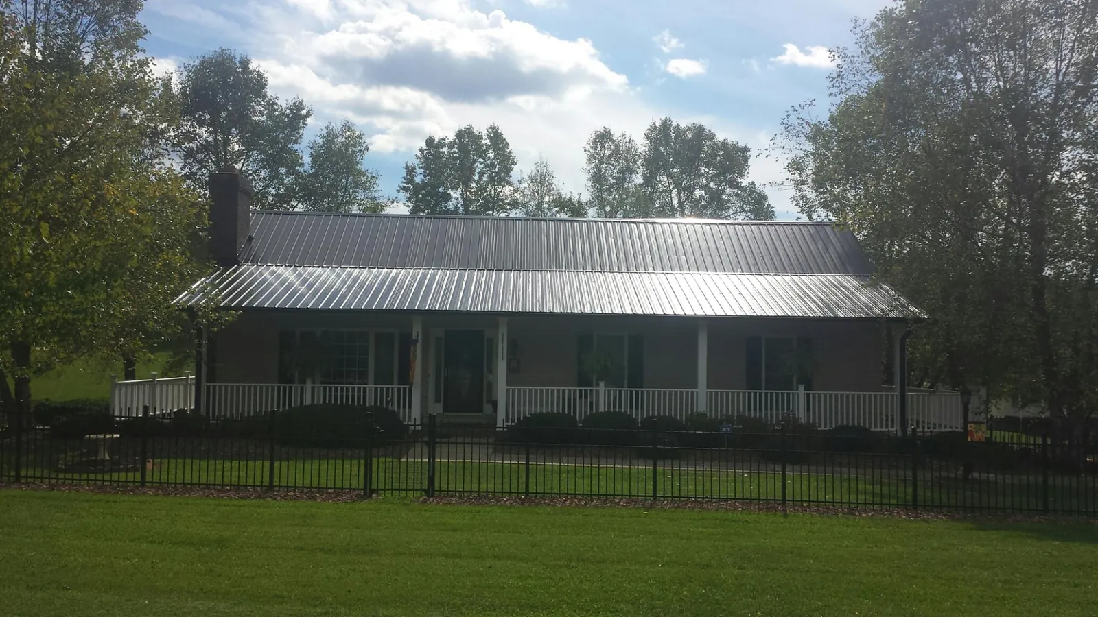 Gray metal roof on a brick ranch with a full width front porch — Gutter Guard Installation work by our crew in Tennyson