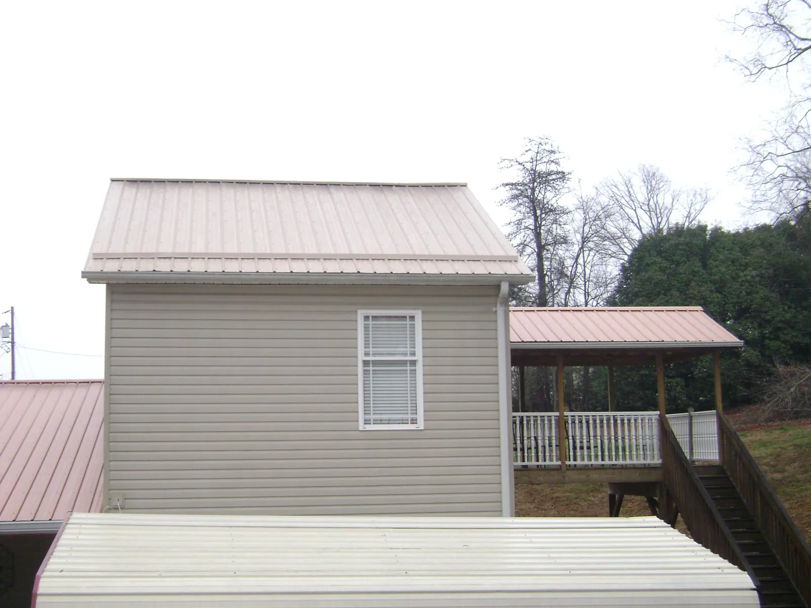 Tan metal roofs on a two story addition and attached porch, from a Roof Replacement job in Tennyson