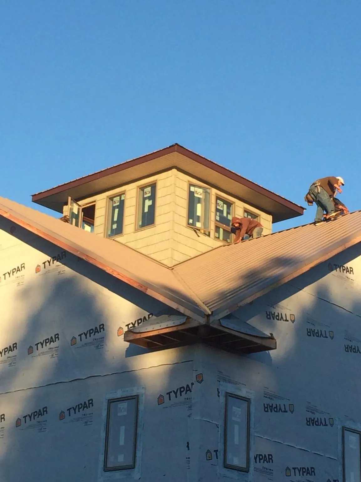 Roofers working around a rooftop cupola on a new metal roof at sunset — Roof Waterproofing in Tennyson by Roofing Brothers